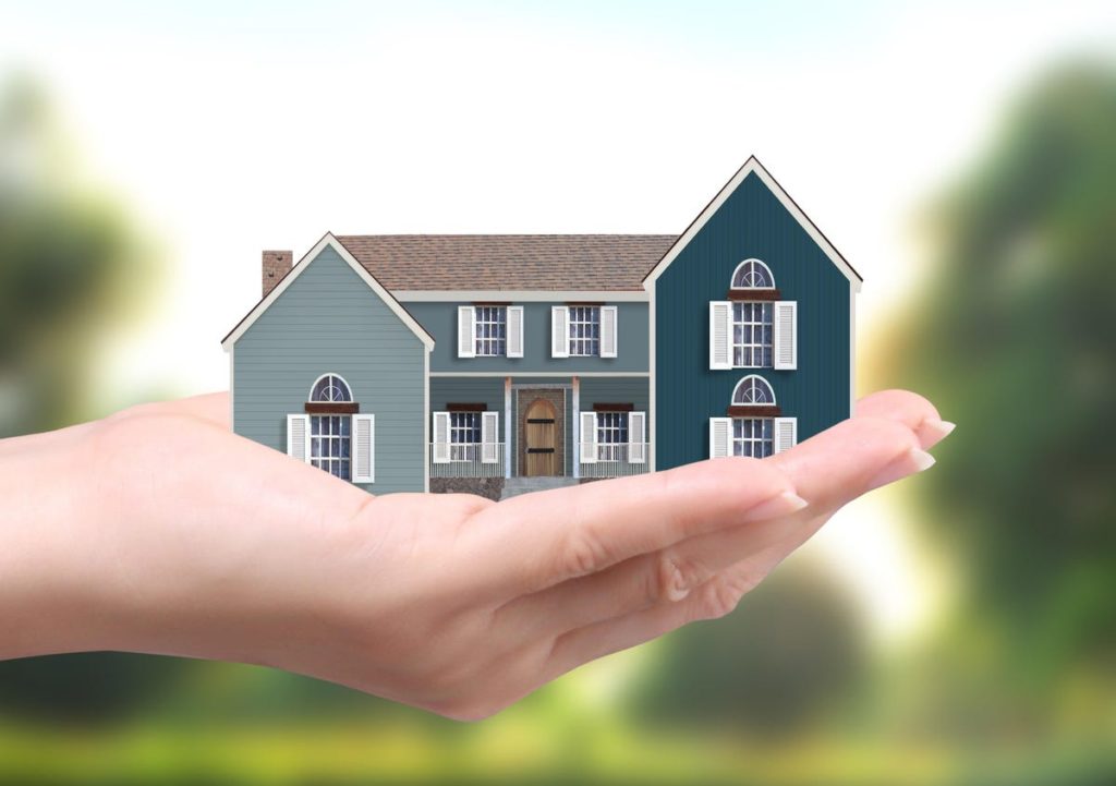 Hands holding a large two-story suburban home representing a jumbo loan mortgage